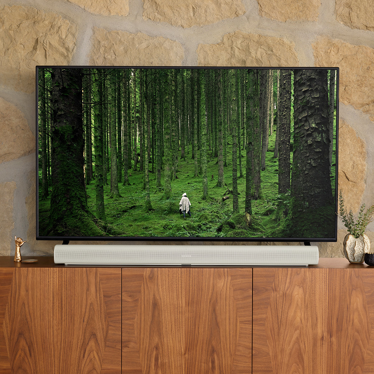 Sonos Arc Soundbar in white on a console table in front of a television