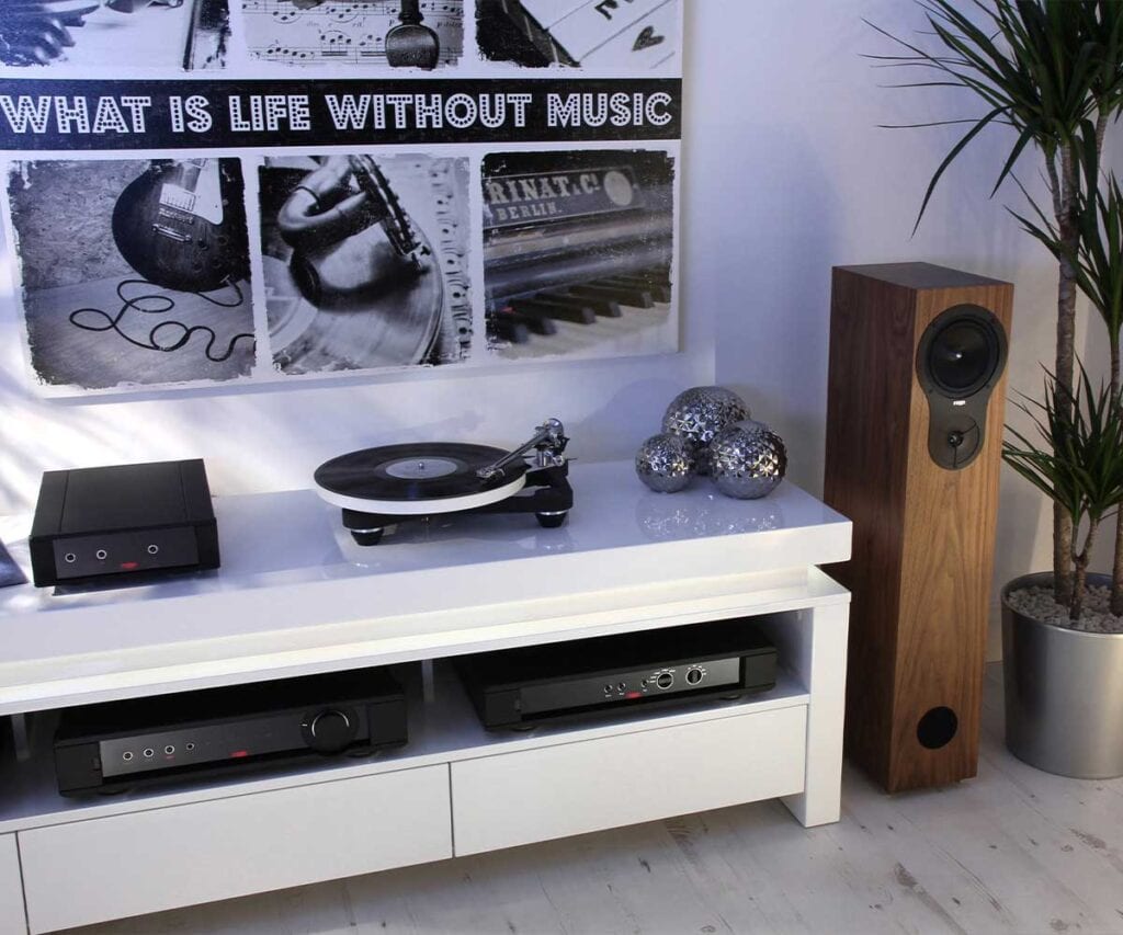 Turntable on top of a white console next to a floorstanding speaker